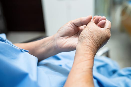 Asian senior or elderly old woman patient pain trigger finger lock her hand while sitting on bed in nursing hospital ward : healthy strong medical concept.