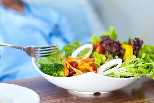 Asian senior or elderly old lady woman patient eating breakfast vegetable healthy food with hope and happy while sitting and hungry on bed in hospital.