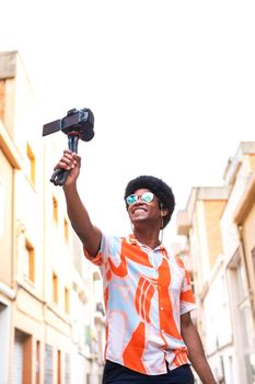 Young African American man vlogging his vacation trip for social media platform. Copy space. Vertical image. Lifestyle concept.
