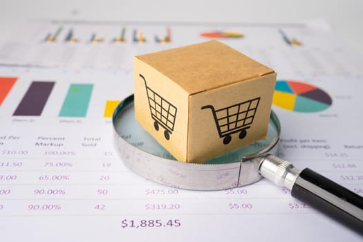 Shopping cart box with magnifying glass on chart graph background, business import export investment online finance concept.