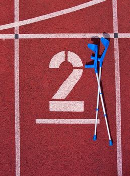 Medicine crutch. Number two. Big white track number on red rubber racetrack. Gentle textured running racetracks in athletic stadium.