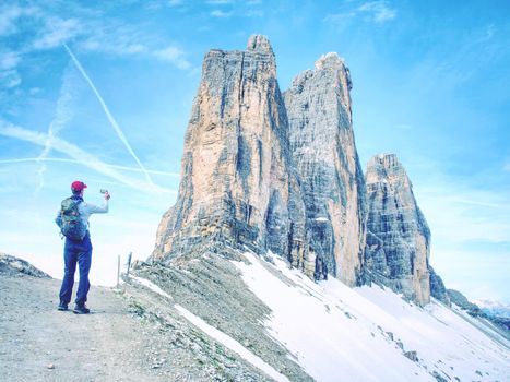 Hiker with backpack climbing on mountain peak. Summits of Dolomites Alps mountains. Tourist walk with heavy backpack