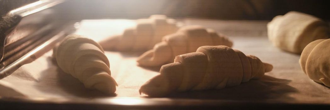 Cooking sweet tasty croissants in oven. Fresh baked croissants in a bakery. Bakery industry and confectionery
