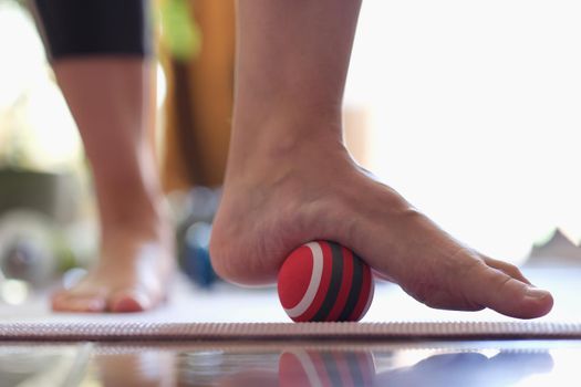 Man massages feet with small ball. Therapeutic massage of the lower extremities. Exercises for foot massage and myofascial therapy.