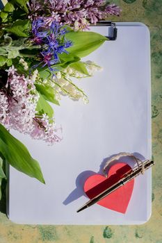 Mock up letter with a love box in the shape of a heart lies on a wooden white table with gypsophila flowers, a greeting card for Valentine's Day with a place for your text. Flat lay, top view photo.