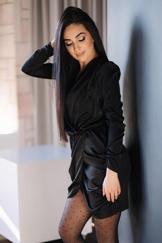 Beautiful brunette woman in elegant black dress. Female with evening makeup.