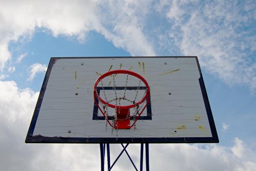 Old worn basketball hoopand  blue sky in background