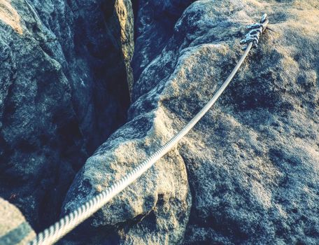 Srew with steel rope anchored into rocky wall. Difficult way on a exposed ridge in Via Ferrata 