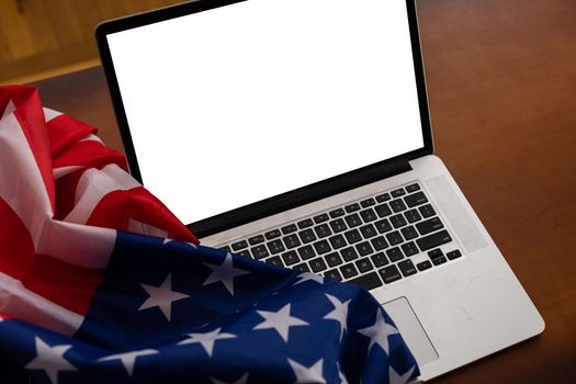 Laptop with blank screen and USA flag on desk in office.