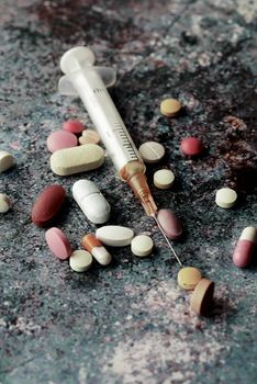 syringe and pills on dark background, close up.