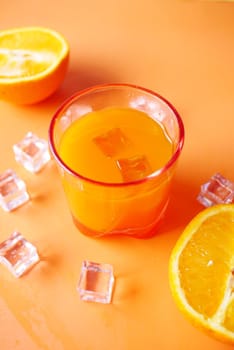 top view of a glass of orange juice with ice on color background.