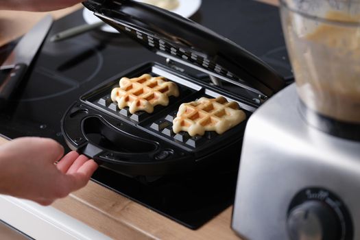 Cooking waffles in waffle iron at home. Electric waffle maker for Viennese and Belgian waffles concept
