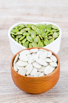 The Pumpkin seeds green and unpeeled in wooden bowl.