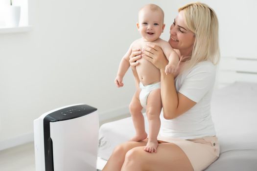 mother and baby near air purifier at home