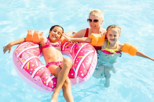 Happy family playing in blue water of swimming pool on a tropical resort at the sea. Summer vacations concept