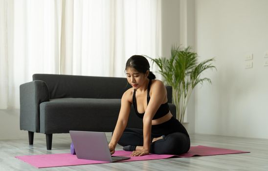 Asian woman with laptop computer at yoga studio - fitness, technology and healthy lifestyle concept.