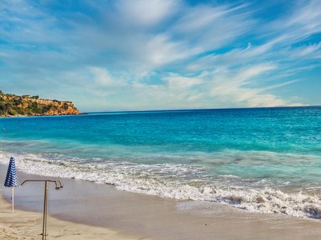 Pair of sun loungers and a beach umbrella on a deserted beach in Kefalonia island