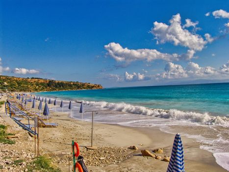 Pair of sun loungers and a beach umbrella on a deserted beach in Kefalonia island