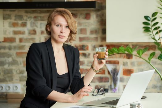 A young woman working remotely in her kitchen. A female boss drinking coffee before a video conference with her employees at home. A female teacher preparing for an online lecture..