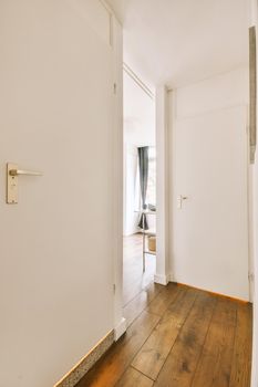 Interior of contemporary corridor in minimal style with narrow hallway with white walls and parquet floor