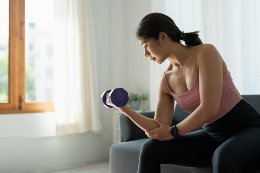 home workout concept asian woman in living room with lifting dumbells mental health in quarantine.