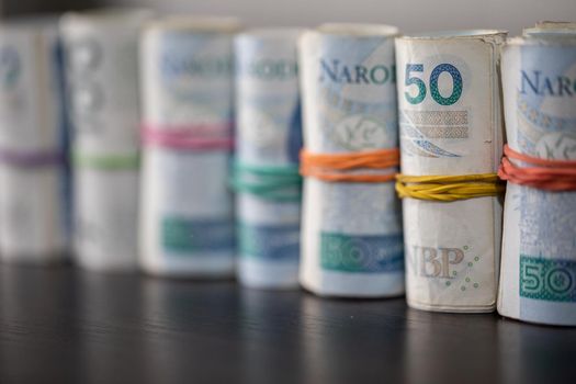 Oblique view of several rolls of fifty and one hundred zloty banknotes. Poland's national paper cash.