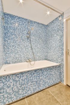 Small bedroom tiled with blue tiles in the form of a mosaic in a modern house