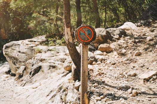 No smoking wooden sign post on a mountain footpath. Ecological sign board forbidding smoking in the area.