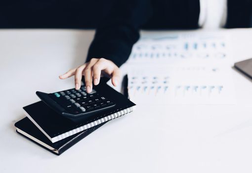 accountant, Auditor, Self-Employed, Finance and Investment, tax calculation and budget, Asian female entrepreneur using a calculator to calculate. Company business results document