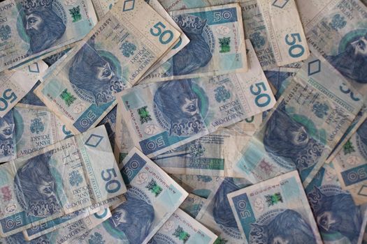 Many Polish banknotes laid flat on a table. View from above. Background of banknotes lying irregularly stacked.
