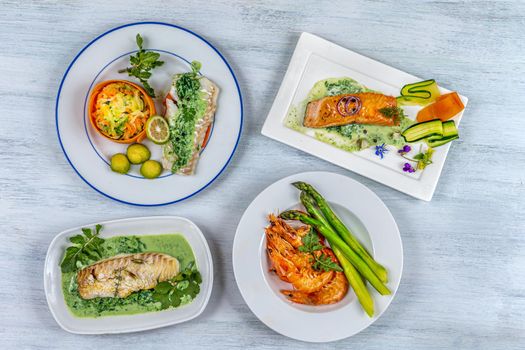 Cod, salmon, shrimp, vegetable assotis in plates in a row.