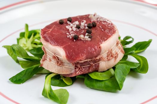 Close-up of a raw tournedos placed on the chew.