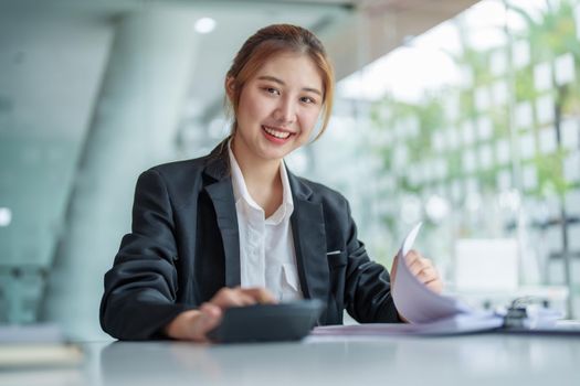 accountant, Auditor, Self-Employed, Finance and Investment, tax calculation and budget, Portrait of Asian female entrepreneur using a calculator to calculate. Company business results document