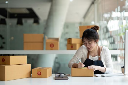 Starting Small business entrepreneur freelance, Portrait young asian woman working at home office with computer, online, marketing, packaging, delivery, SME, e-commerce concept.
