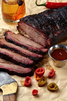 Fresh Brisket BBQ beef sliced for serving against a kraft paper background with sauce, hot peppers and corn. Generous accommodation for copy space. American style