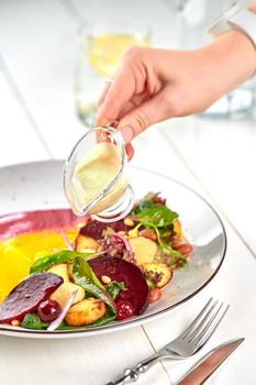 Healthy diet: colorful beetroot salad with potatoes and shredded leaves in a white plate on a white wooden table