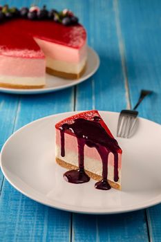 Cheesecake with blueberries on a white plate on a blue wooden background. Fresh berries. Still life