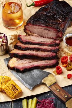 Fresh Brisket BBQ beef sliced for serving against a kraft paper background with sauce, hot peppers and corn. Generous accommodation for copy space. American style