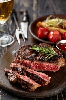 Juicy steak medium rare beef with spices on wooden board on table. dry aged. Served with potatoes, beer, and tomato sauce. Still life