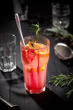 Pink fruit cocktail or lemonade on black wooden table. Pineapple with orange. Still life