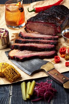 Fresh Brisket BBQ beef sliced for serving against a kraft paper background with sauce, hot peppers and corn. Generous accommodation for copy space. American style