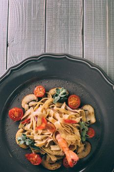 Noodles with shrimp and mushrooms. The original presentation of the dish from the chef. Spaghetti