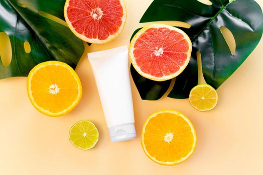 Moisturizing cream with vitamin c in a tube with citrus fruits and orange slices on a colored background. Flat lay, top view
