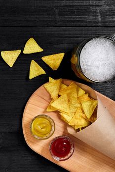 Glass of beer with nachos chips on a wooden background. Top view. Copy space. Still life. Flat lay