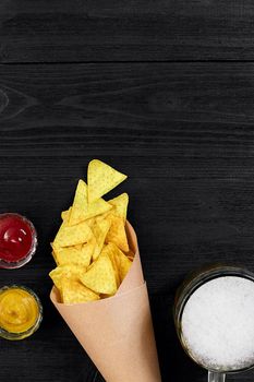 Glass of beer with nachos chips on a wooden background. Top view. Copy space. Still life. Flat lay