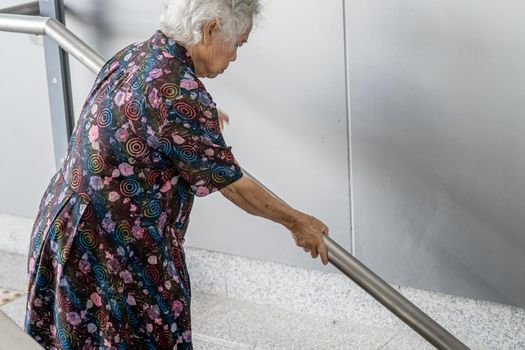 Asian senior or elderly old lady woman patient use handle at stairs security support in building, healthy strong medical concept.