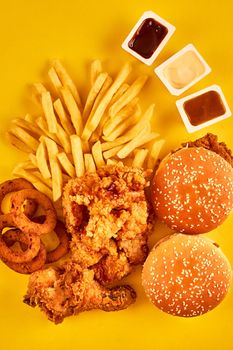 Top view hamburger, french fries and fried chicken on yellow background. Copy space for your text. Still life. Flat lay. Menu or receipt background