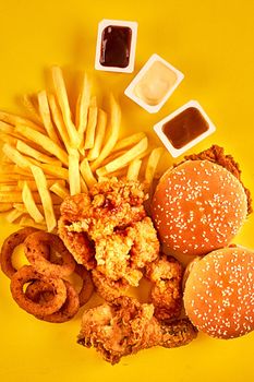 Top view hamburger, french fries and fried chicken on yellow background. Copy space for your text. Still life. Flat lay. Menu or receipt background