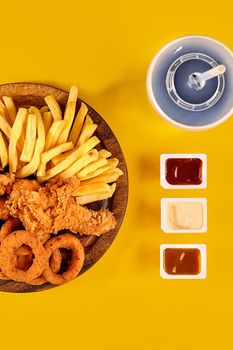 Fast food dish on yellow background. Fast food set fried chicken and french fries. Take away fast food. Top view. Copy space. Still life. Flat lay.