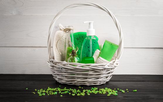 Green composition beauty treatment products in green colors: shampoo, soap, bath salt, oil. Various bath accessories. Items for the spa. Still life. Copy space